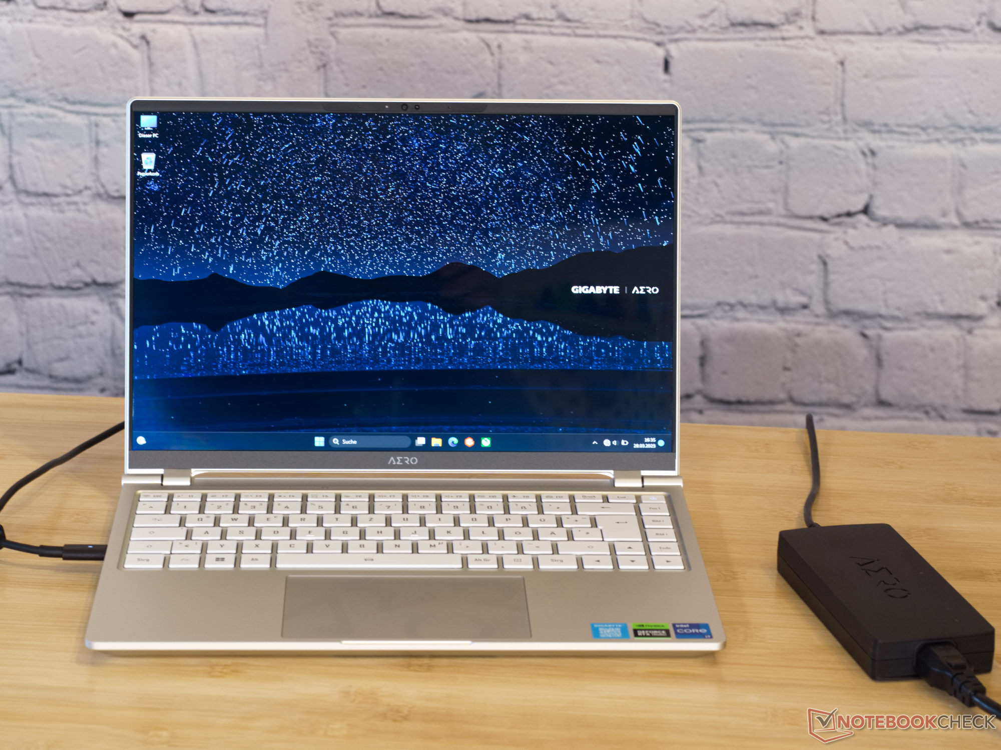Ordenador portátil negro con gráficos verdes. La pantalla muestra la palabra "AERO". El portátil tiene un teclado iluminado en verde.